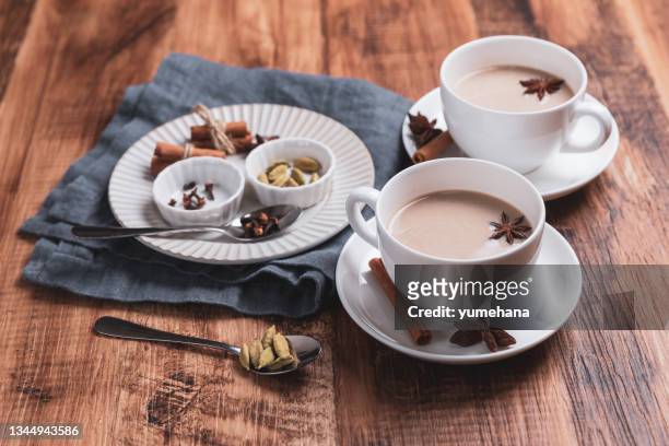 tè indiano masala chai. tè speziato con latte sul tavolo rustico in legno. - masala tea foto e immagini stock