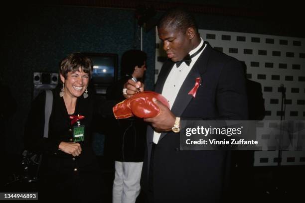 American boxer Riddick Bowe signs a boxing glove for a press member during the Second Annual Jim Thorpe Pro Sports Awards at the Wiltern Theater in...