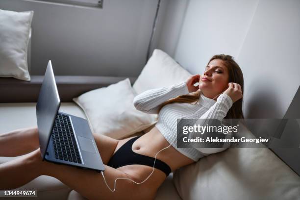 musikzeit auf laptop für schöne frau, die zu hause in unterwäsche sitzt - verführerische frau stock-fotos und bilder
