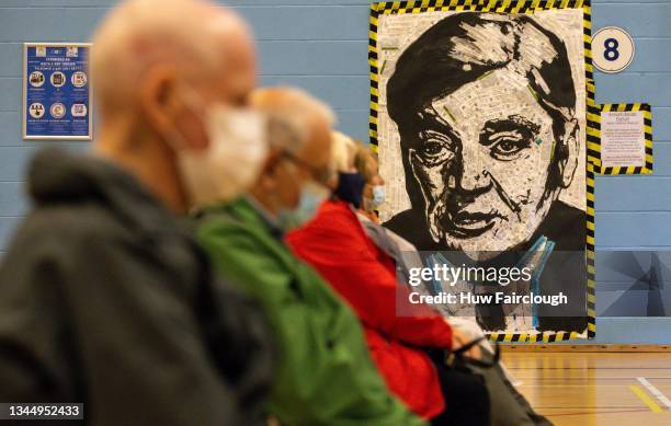 Patients sit in front of a portrait of Aneurin Bevan the architect of the NHS after receiving their boost vaccines on October 05, 2021 in Cwmbran,...