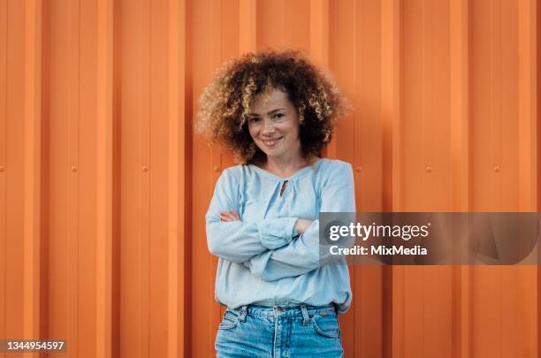 portrait of a beautiful, curly haired girl - oranje achtergrond stockfoto's en -beelden