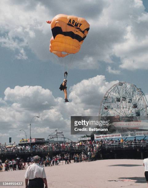 Watched by a crowd of people on the broadwalk and beach, US Army Golden Knight Betty Ann Fox parachuting at Coney Island, New York, US, 2nd August...