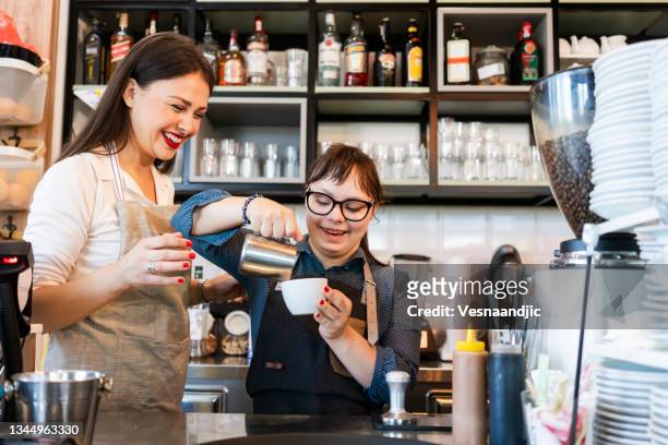 joven con síndrome de down que trabaja en un café preparando café - diversidad funcional fotografías e imágenes de stock