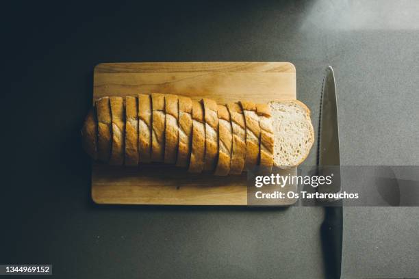 sliced bread on a cutting board with a bread knife on the kitchen counter. - bread knife stock pictures, royalty-free photos & images