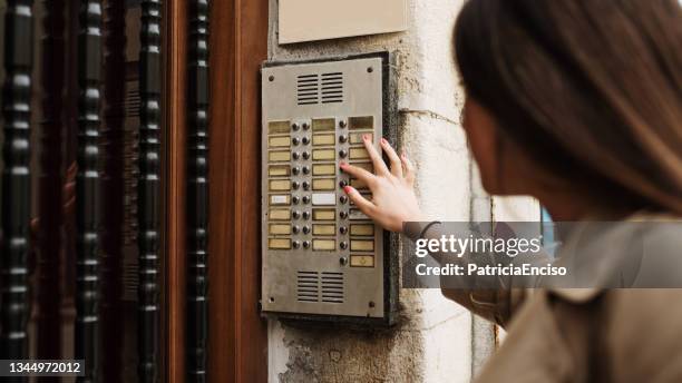 young woman calling an apartment intercom - intercom stock pictures, royalty-free photos & images