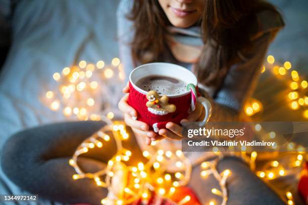 a mug in a mug cosy with coffee inside being held by a person - americano stockfoto's en -beelden