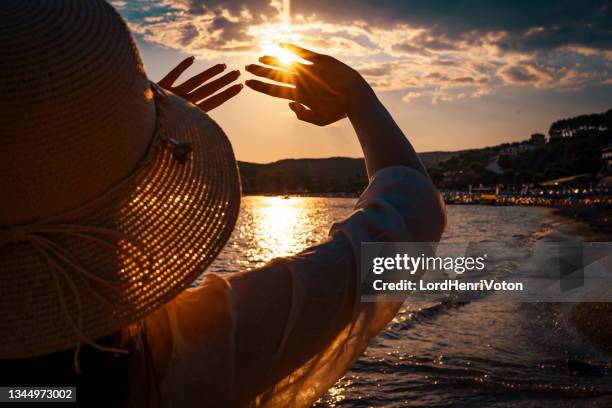 frau blockiert sonne mit den händen - hands sun stock-fotos und bilder