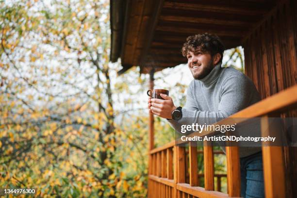 young man drinking tea in fall morning - railings stock pictures, royalty-free photos & images