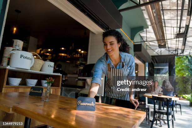 waitress putting a reserved sign on a table at a restaurant - reserved stock pictures, royalty-free photos & images