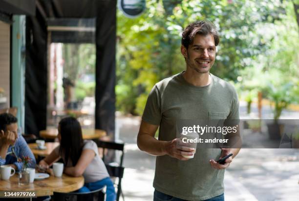 happy man buying a cup of coffee to go at a cafe - leaving restaurant stock pictures, royalty-free photos & images