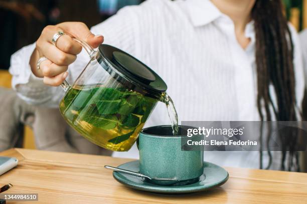 pouring green tea with mint from a glass teapot. - green tea stock pictures, royalty-free photos & images
