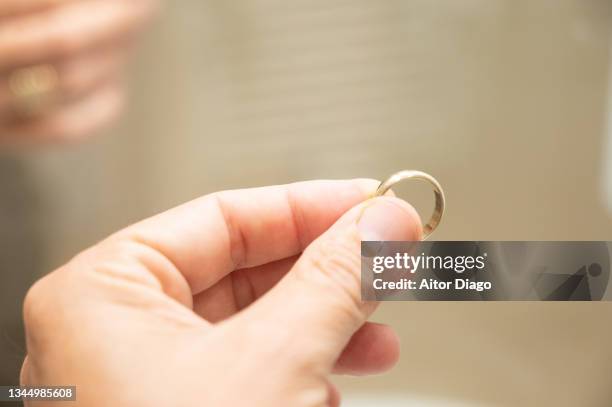 a man holds a wedding ring in his hand. - trauringe gold stock-fotos und bilder