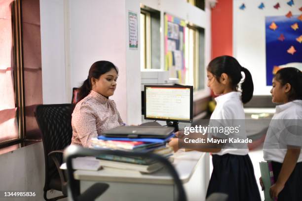 school girl borrowing a book from the librarian in a school library - bibliotecário imagens e fotografias de stock