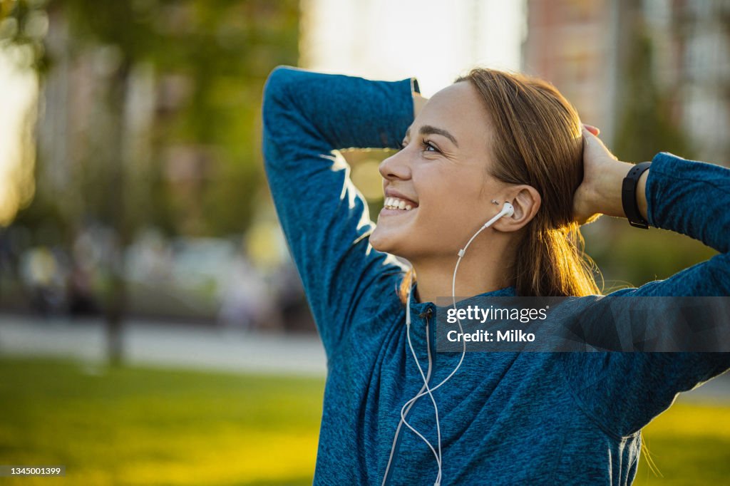 Portrait of a young woman stretching in a park after a sports activity
