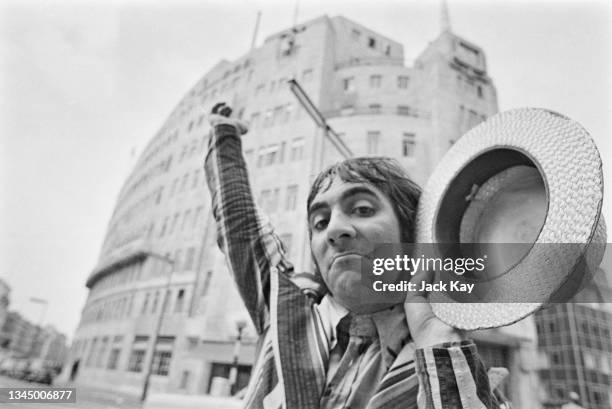 British drummer Keith Moon , of the British rock band The Who, wearing a striped blazer with one arm outstretched with the other holding a straw...