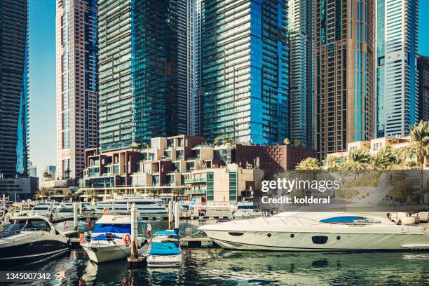 dubai marina surrounded by modern buildings, luxury yachts moored in marina - dubai marina stock pictures, royalty-free photos & images
