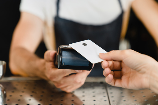 Cashless payment method. Closeup shot of micro ATMs while customer paying with credit card in bar restaurant cafe. E-commerce e-banking concept.