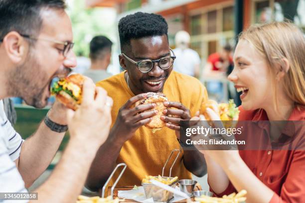 amigos y comida rápida - amigos hombres en restaurant fotografías e imágenes de stock