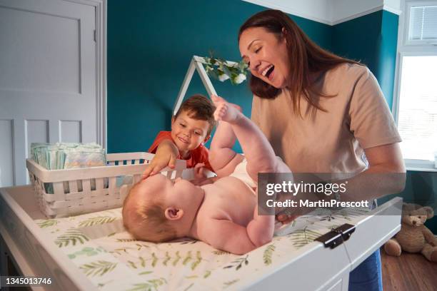 helping mummy changing baby - two kids with cycle imagens e fotografias de stock