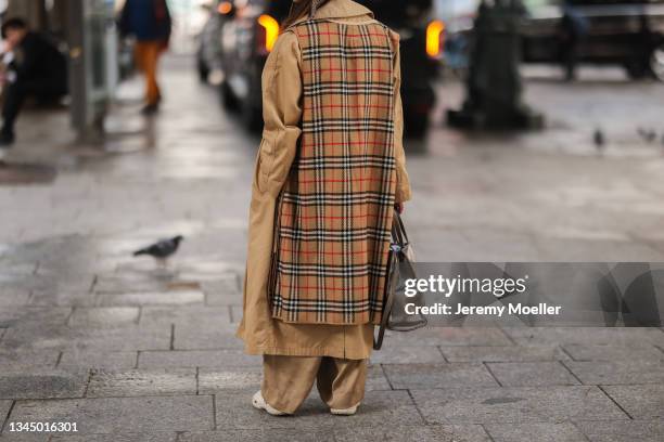 Fashion Week Guest wearing a brown hat, a beige burberry trenchcoat, beige pants outside Ester Manas on October 02, 2021 in Paris, France.