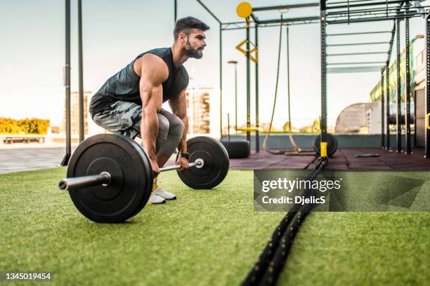 junger bodybuilder beim kreuzheben im fitnessstudio im freien. - weightlifting stock-fotos und bilder