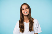 Cheerful caucasian schoolgirl teenager pupil student smiling with toothy smile looking at camera isolated. Cutout portrait in blue background