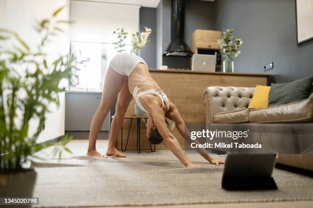 woman doing yoga in downward facing dog pose at home - upright position stock pictures, royalty-free photos & images