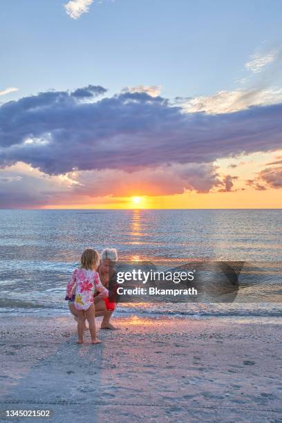 niño pequeño y madre durante una vibrante puesta de sol en sand key beach en clearwater florida ee. uu. - clearwater beach fotografías e imágenes de stock