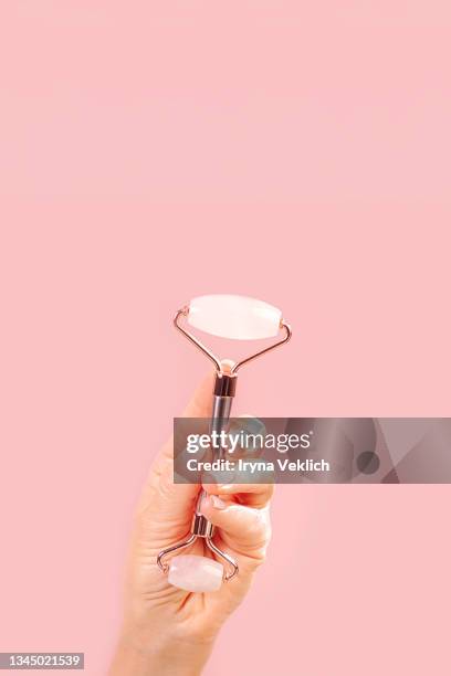 female hand with rose quartz facial jade roller. - 玉石滾��輪 個照片及圖片檔