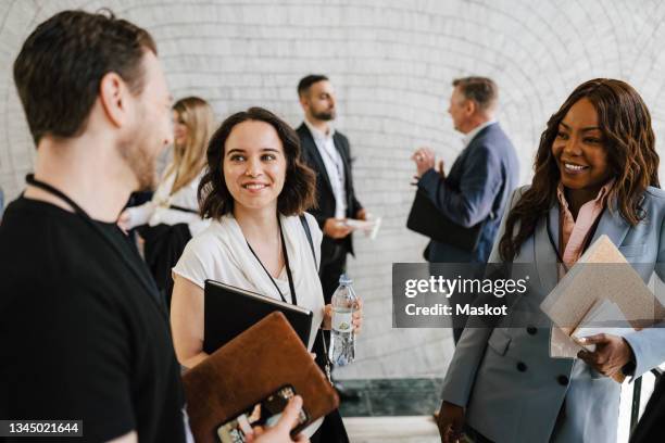 smiling businesswomen looking at male professional discussing during networking event - business conference - fotografias e filmes do acervo