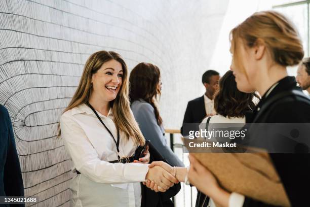 happy pregnant female entrepreneur greeting businesswoman while doing handshake during networking event - medium group stock pictures, royalty-free photos & images