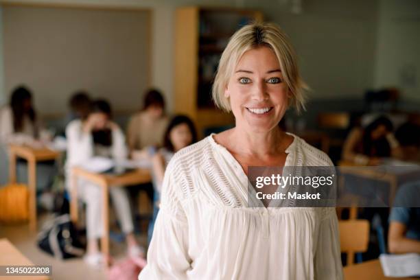 portrait of smiling female teacher in classroom - classroom-front-view stock-fotos und bilder