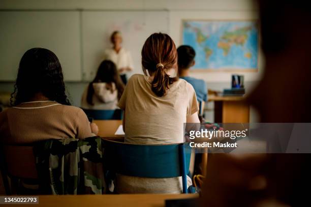 rear view of teenage girls and boys learning in classroom - highschool stock pictures, royalty-free photos & images