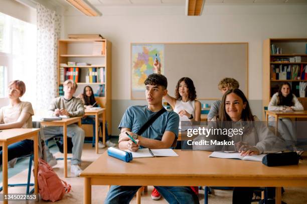 girls and boys learning while sitting at desk in classroom - classroom-front-view stock-fotos und bilder