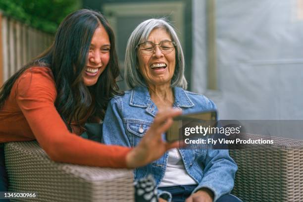 mom and daughter using smart phone to video call family - hawaiiaanse etniciteit stockfoto's en -beelden