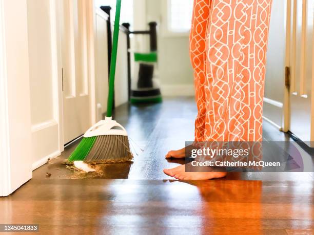 young mixed-race female sweeps dirt & debris in hallway leading to family’s mudroom - sweeping dirt stock pictures, royalty-free photos & images