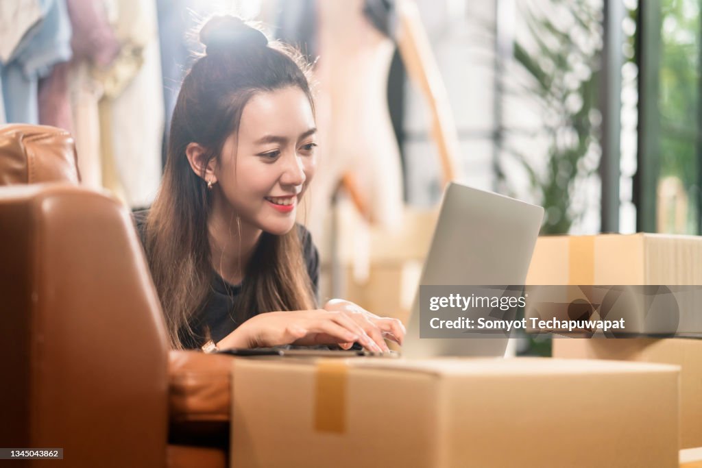 Asian female happiness smiling with order from client order keying with laptop small business E-Commerce and Online Shopping,asian female online cloth shop owner working at home studio with cheerful moment