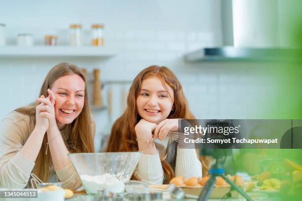 mom and daughter preparing cake bread together at home video calling to father,mother and daughter girl teenager are cooking cookies and having fun in the kitchen. homemade bakery family recipes weekend activity stay home concept - broken friendship stock pictures, royalty-free photos & images