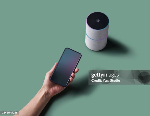 woman using a smart speaker with smart phone. - ai speaker stock-fotos und bilder