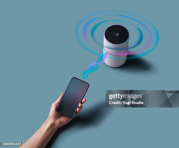 woman using a smart speaker with smart phone. - bluetooth stock-fotos und bilder