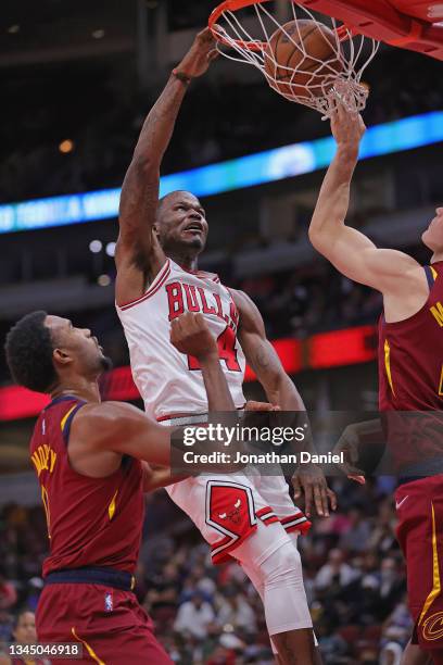 Javonte Green of the Chicago Bulls dunks between Evan Mobley and Lauri Markkanen of the Cleveland Cavaliers during a preseason game at the United...