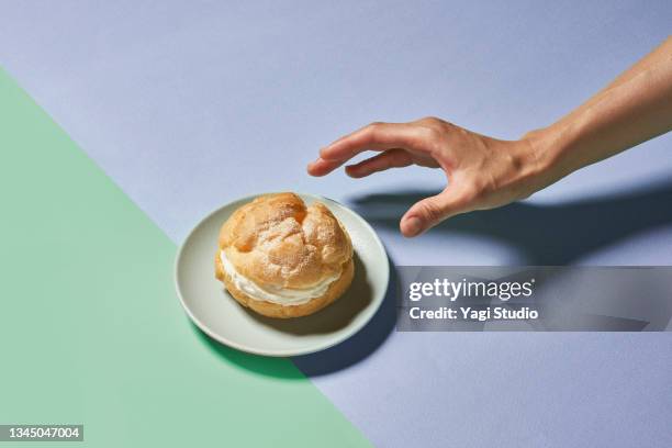 cream puff and hand on a colorful background. - plate in hand stockfoto's en -beelden