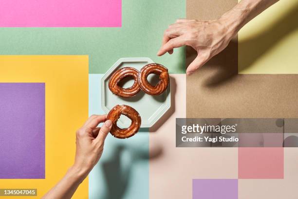 churros on a colorful background with hands. - donut man bildbanksfoton och bilder
