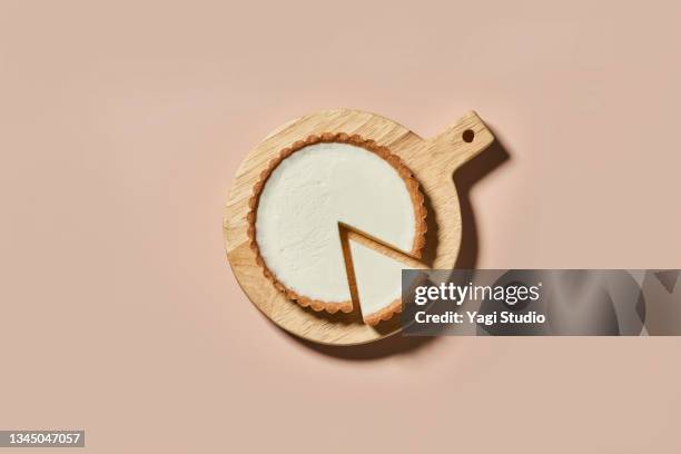 overhead shot of rare cheese cake on a round wood board - cheesecake stock pictures, royalty-free photos & images