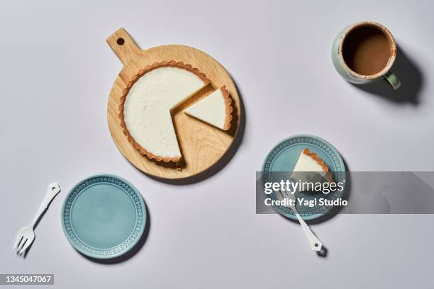 overhead shot of rare cheese cake on a round wood board with coffee and dish. - koffiekoek stockfoto's en -beelden