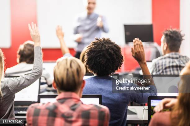 rear view of students raising their arms on a computer class. - student behind laptop stock pictures, royalty-free photos & images