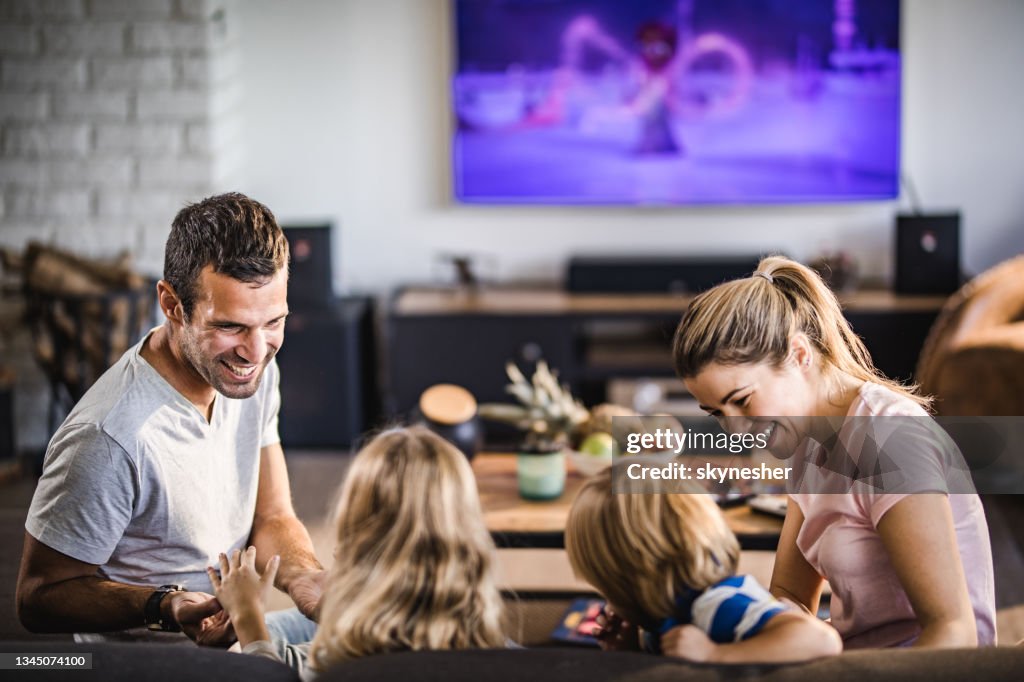 Glückliche Eltern, die Spaß mit ihren Kindern im Wohnzimmer haben.