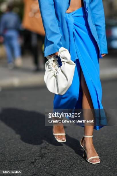 Angela Gonzalez wears a blue oversized blazer jacket, a high waist matching blue slit / split flowing skirt knot on the waist, a white leather puffy...