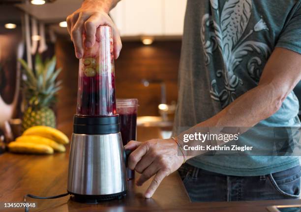 man using blender to make fruit smoothies for breakfast, close-up of hands - blender stock pictures, royalty-free photos & images