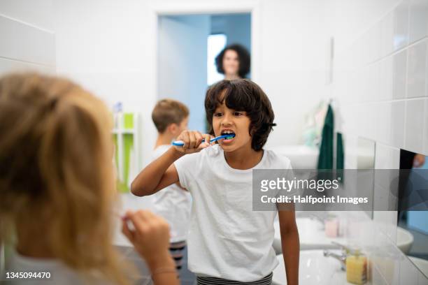 preschool children brushing their teeth indoors at nursery bathroom. - casa famiglia foto e immagini stock